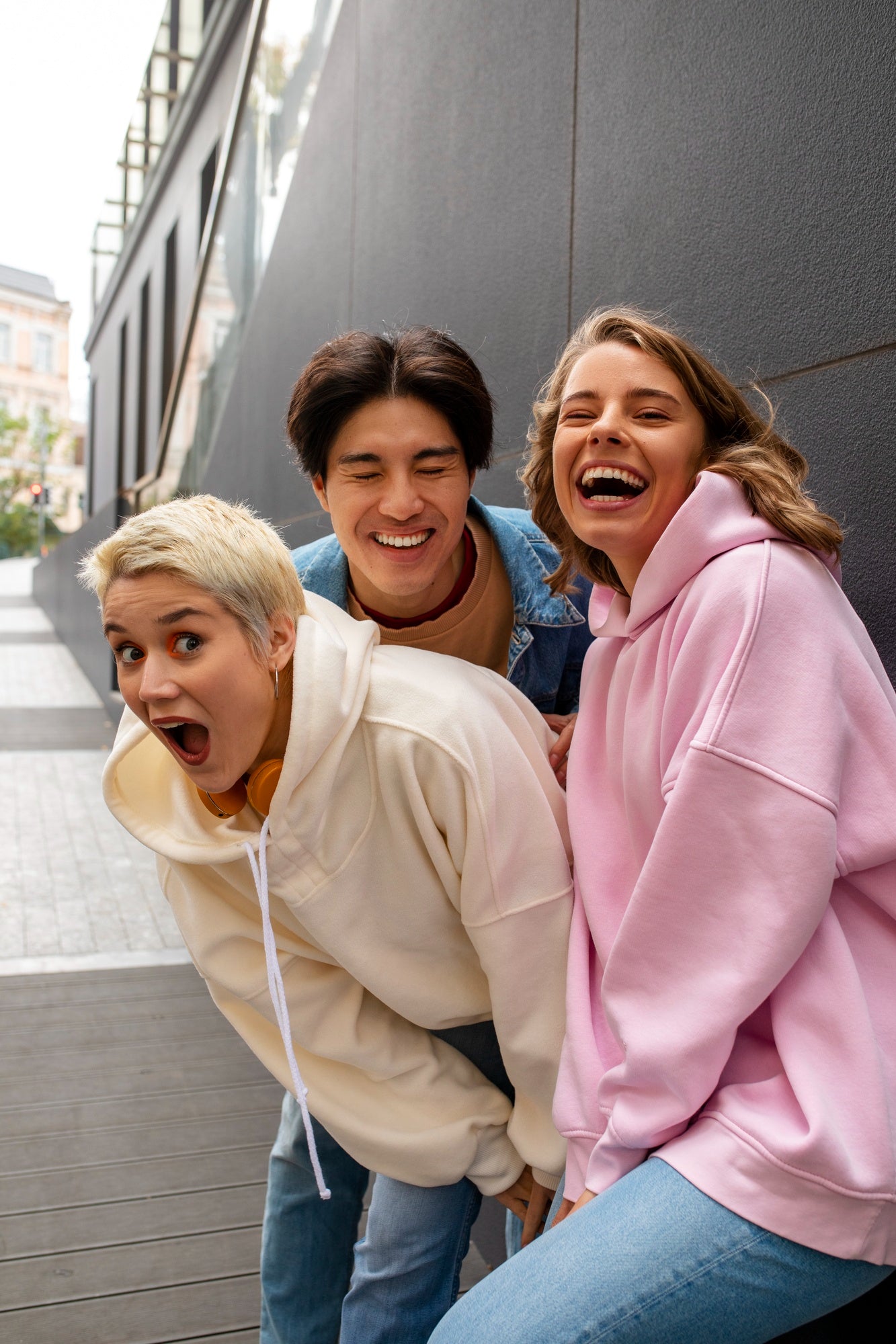 Three friends in colorful hoodies posing together outdoors.